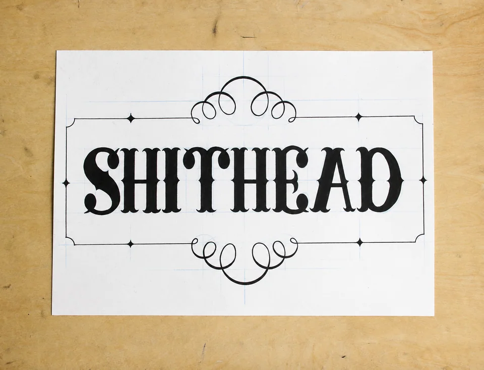 Finished black ink SHITHEAD lettering and ornamental frame