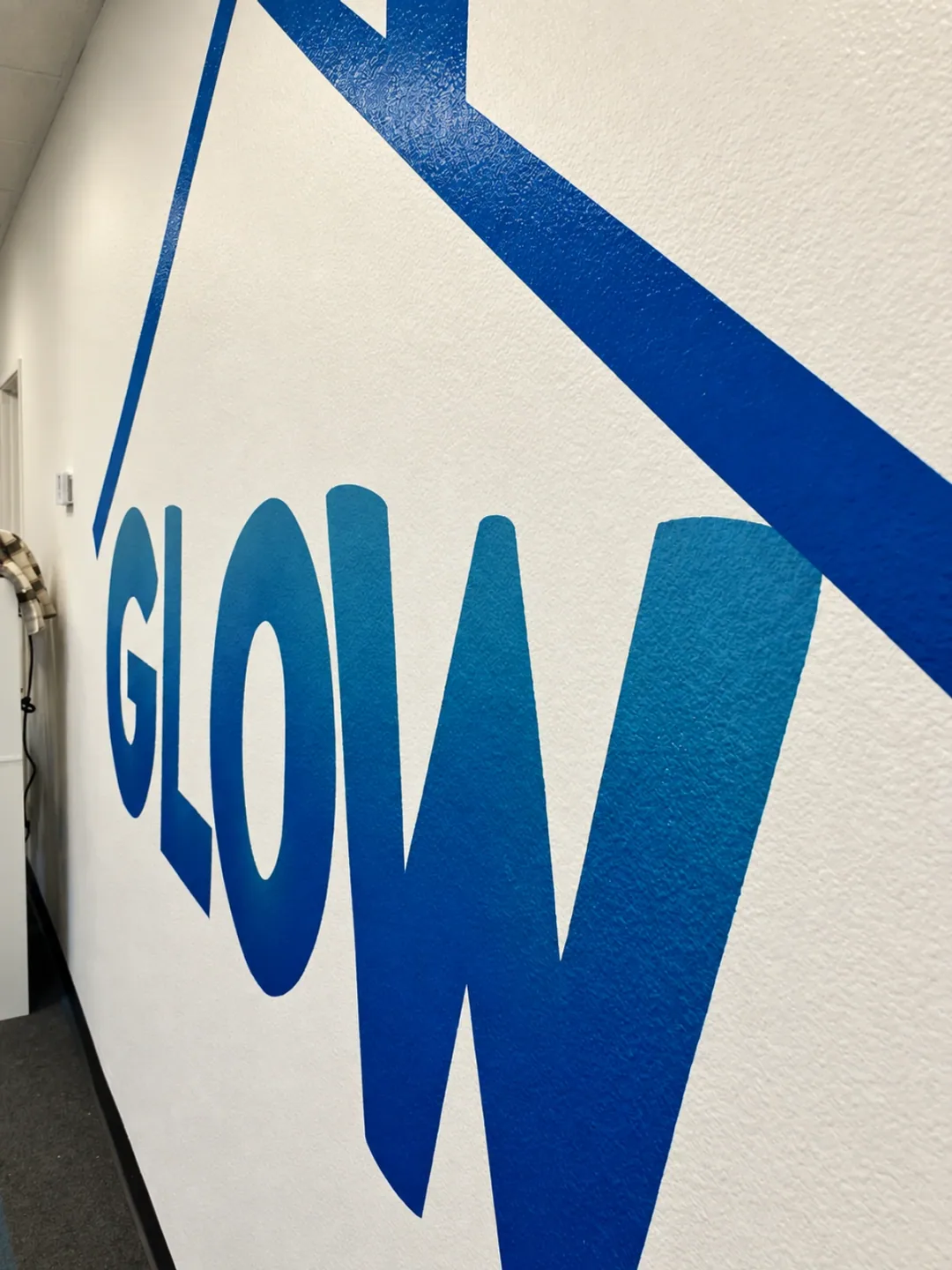 Skewed close-up of the blue Glow mural painted on a textured wall