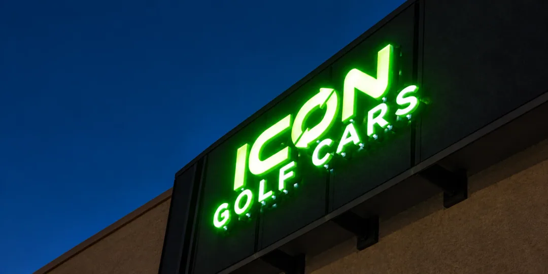 The complete illuminated Icon Golf Cars sign at dusk